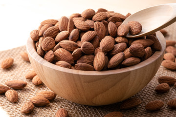 Closeup fresh almonds nut with wooden bowl and spoon.