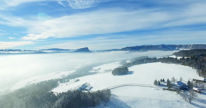 Aerial view of a wide snowy landscape with forest and mountains