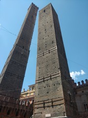 View looking up the twin Bologna towers in Italy against a blue summer sky