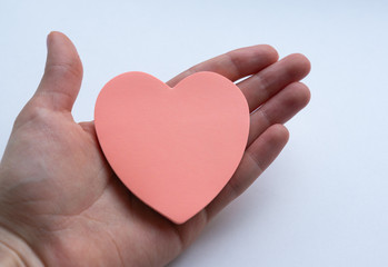 Woman's hand holding pink heart-shaped sticky notes on white background. Concept of love, minimalism.