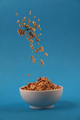 granola pouring to the white bowl against blue background