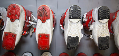Ski boots of various colors installed in a row with the soles up in the rental of ski equipment....