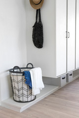  Laundry basket with dirty clothes in a white room corner.