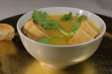Vegetable soup with toasted bread in a bowl with spoon accompanied by celery over the soup
