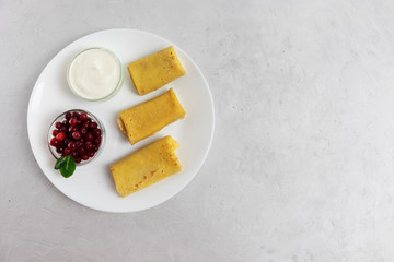 Pancakes with sour cream and cranberries on a white plate, preparation for Shrovetide
