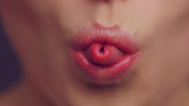 Woman blowing air with her bent tongue, closeup slow motion