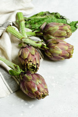 Obraz premium Fresh artichokes on a light stone table. . organic seasonal vegetables. artichoke recipe. selective focus