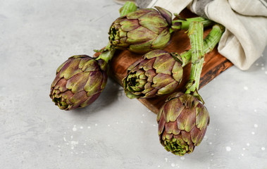 Fototapeta premium Fresh artichokes on a light stone table. . organic seasonal vegetables. artichoke recipe. selective focus