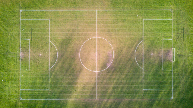 Football pitch. Aerial drone view looking down vertically onto an empty soccer pitch with shadows cast by the low sun.