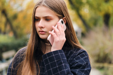 Portrait of sad girl talking on cellphone outdoor