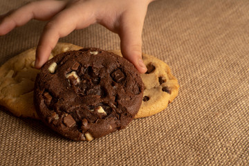 a children hand picking chocolate chip cookies