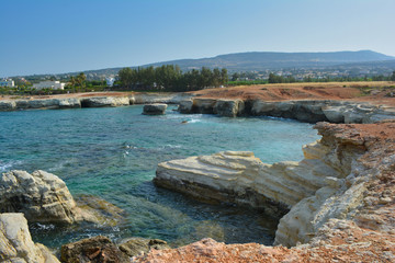 sea Bay surrounded by sea caves against the background of distant mountains and cloudless blue sky