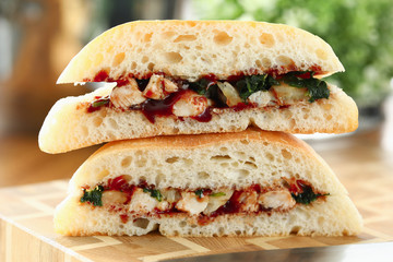 Cut chiken sandwich with ketchup against kitchen closeup background.