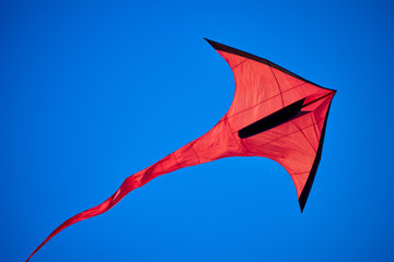 Red, arrow shaped kite in the blue skies