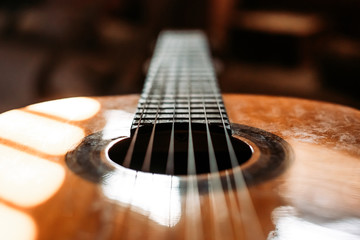 Close up of classical guitar head with sound hole and stings. Blurred background