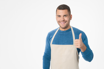 Young handsome shopkeeper man wearing apron doing thumb up gesture standing over isolated white background