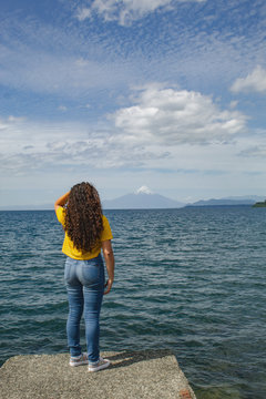 Mujer crespa mirando el horizonte en puerto varas y el volcan osorno