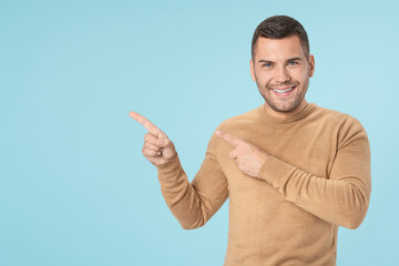 Fototapeta premium Young adult man pointing with fingers and looking at camera isolated on blue background
