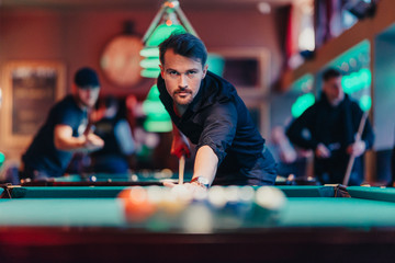 A man tries his hand at playing billiards. He is accompanied by various emotions, satisfaction, anger, frustration, focus. The décor of the place where the game gives the fun a unique character.