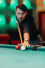 A man tries his hand at playing billiards. He is accompanied by various emotions, satisfaction, anger, frustration, focus. The décor of the place where the game gives the fun a unique character.