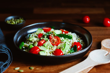Healthy salad with bulgur, avocado, spinach and cherry tomatoes.