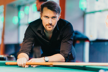 A man tries his hand at playing billiards. He is accompanied by various emotions, satisfaction, anger, frustration, focus. The décor of the place where the game gives the fun a unique character.