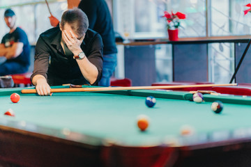 A man tries his hand at playing billiards. He is accompanied by various emotions, satisfaction, anger, frustration, focus. The décor of the place where the game gives the fun a unique character.
