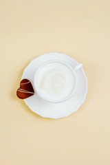 Mug of cappuccino, heart-shaped chocolate chip cookies on a beige background.