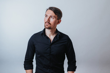 Photo of a handsome man with a coolly stylized scrub and hairstyle. Photo taken in a photo studio on a gray background. The man tries to express his emotions with gesticulation and mimics.