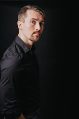 Handsome man. Photo in a photo studio on a black background. A young man expresses his emotions with expressions, gesticulation and attitude.