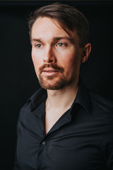 Handsome man. Photo in a photo studio on a black background. A young man expresses his emotions with expressions, gesticulation and attitude.