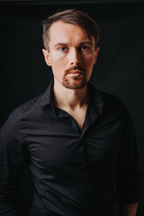 Handsome man. Photo in a photo studio on a black background. A young man expresses his emotions with expressions, gesticulation and attitude.