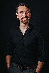 Obraz premium Przystojny mężczyzna. Zdjęcie w studio fotograficznym na czarnym tle. Młody człowiek wyraża swoje emocje mimiką, gestykulacją i postawą.