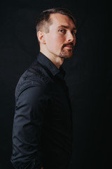 Fototapeta premium Handsome man. Photo in a photo studio on a black background. A young man expresses his emotions with expressions, gesticulation and attitude.