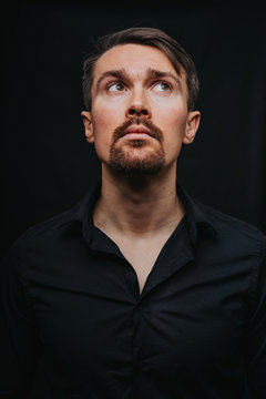 Handsome man. Photo in a photo studio on a black background. A young man expresses his emotions with expressions, gesticulation and attitude.