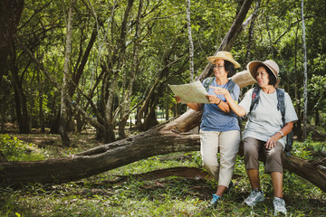 Naklejka na ściany i meble Two elderly women hiking Carrying a backpack and carrying a map. The concept of senior citizens traveling nature