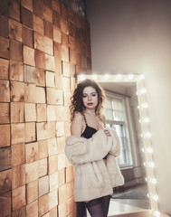 Fototapeta premium glamorous lady in fur coat and stockings posing in the Studio