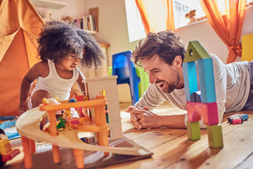 Father and toddler daughter playing with toys on floor