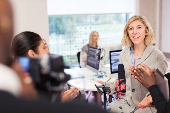Classmates clapping for woman at microphone in journalism class