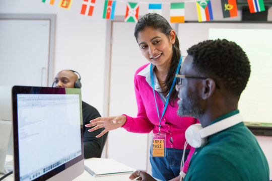 Community college instructor helping student at computer in classroom
