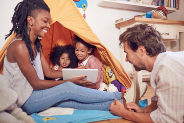 Young family using digital tablet on teepee