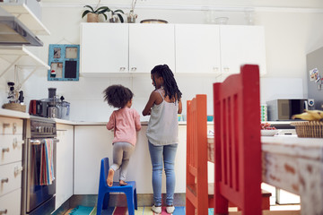 Mother and daughter doing dishes at kitchen sink