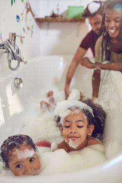 Parents giving daughters bubble bath