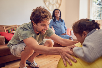 Father and daughter playing with fitness ball