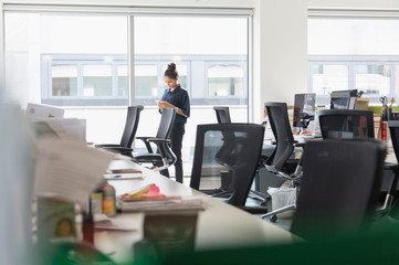 Businesswoman using smart phone at sunny office window