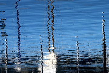 Spiegelungen im schönen blauen Wasser von den Bootsmasten in Friedrichshafen - Bodensee.