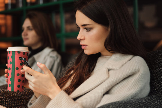 Portrait of businesswoman with coffee intently using cellphone in cefe