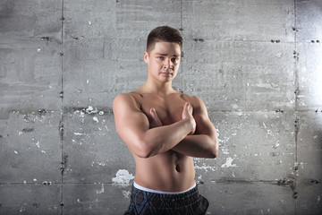 Obraz premium Portrait of a sexy young man with muscular body posing at studio. Gray background. Men's health.