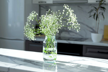 Bouquet of white gypsophila on the kitchen table on a Sunny day. Light and shadows from the window. Trend.