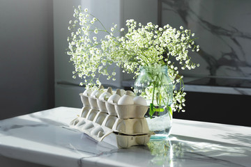 Happy Easter! Decorating the kitchen for Easter on a Sunny day. White egg. Bouquet of white gypsophila. Light and shadows from the window. Trend.